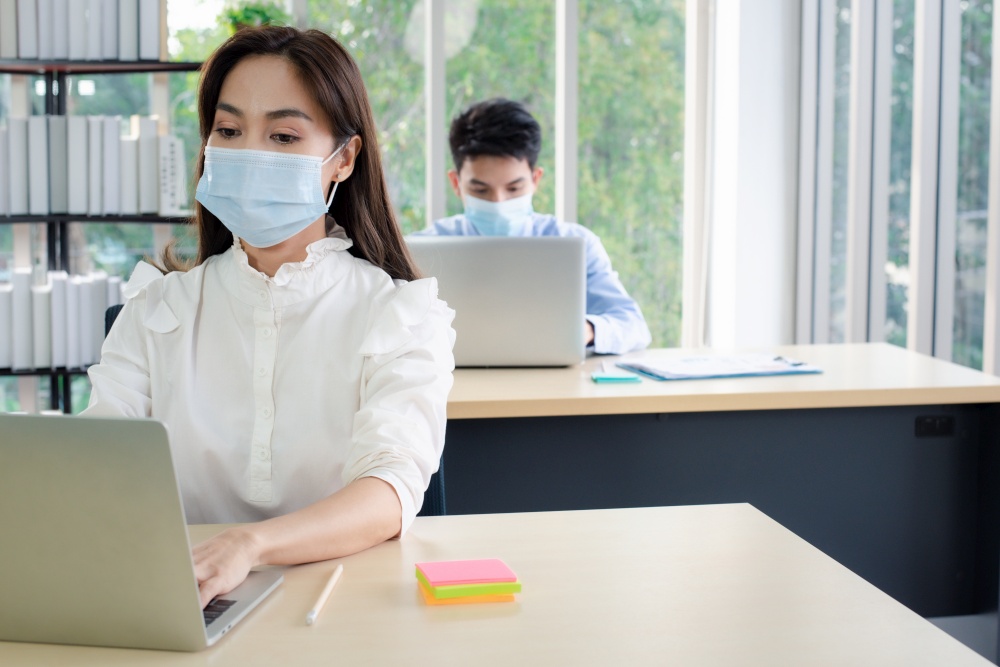Asian business people with medical mask for virus protection working in office. new normal and social distancing concept.