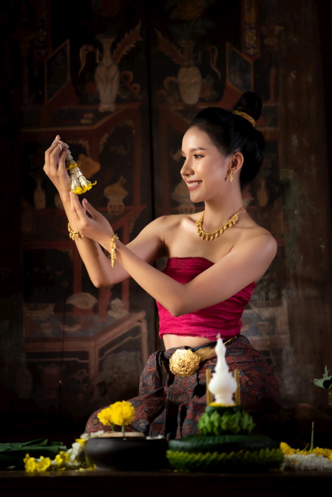 Thai girl in traditional dress costume making and decorating Krathong. Loy Krathong Festival.