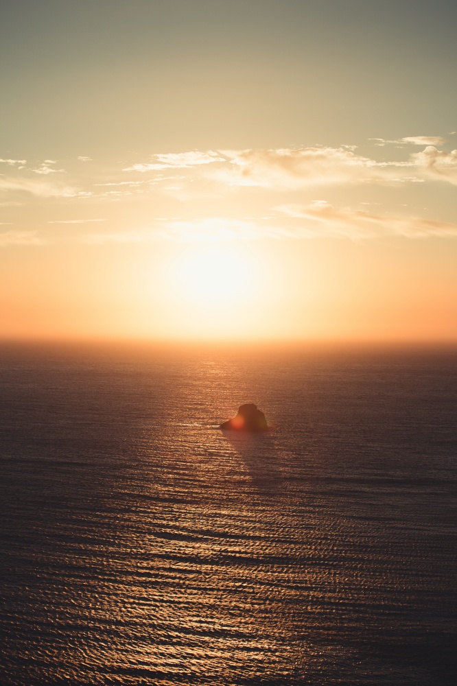 Massive sunset over a lonely rock in the middle of the ocean