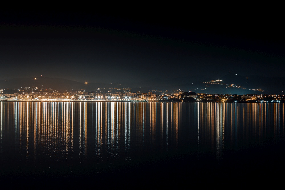 The city skyline lights reflecting in the sea during the night