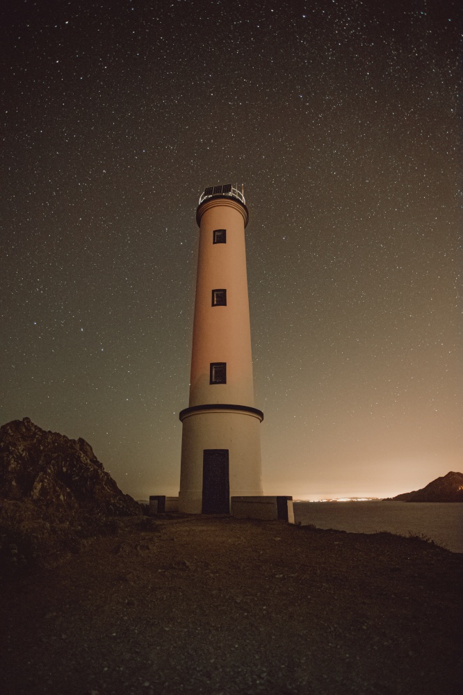 White lighthouse with a sky filled with stars as a background