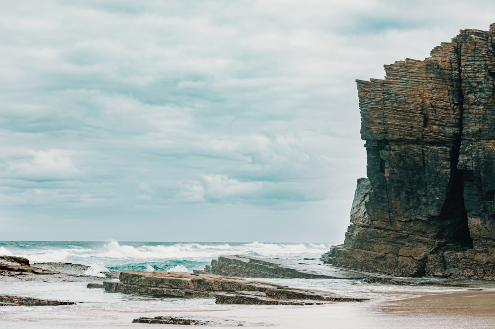A massive cliff near the wild sea in the beach of the cathedrals in spain with copy space