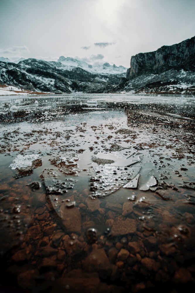 Some frozen water and pieces of ice in a frozen lake in the middle of the mountains during winter