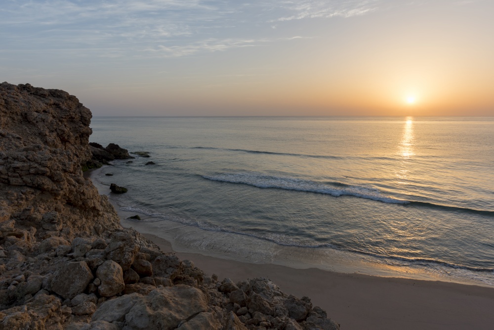 Sunrise over cliffs and sea of Oman (Gulf of Oman) wild coast of Ras Al Jinz, Sultanate of Oman. Sunrise over the wild coast of Ras Al Jinz, Oman