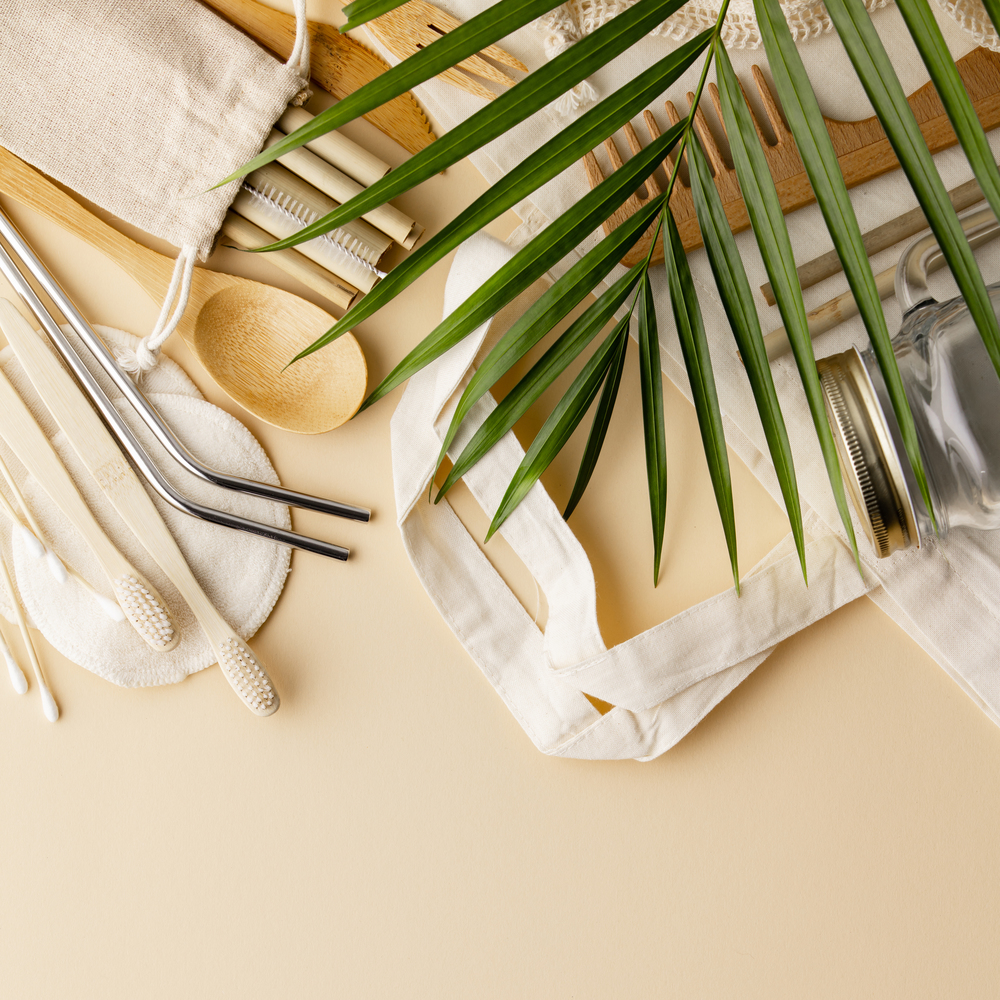 Zero waste concept. Cotton bag, bamboo cultery, glass jar,  bamboo toothbrushes, hairbrush and straws on color background, flat lay, copyspace. Plastic free. Sustainable lifestyle concept.