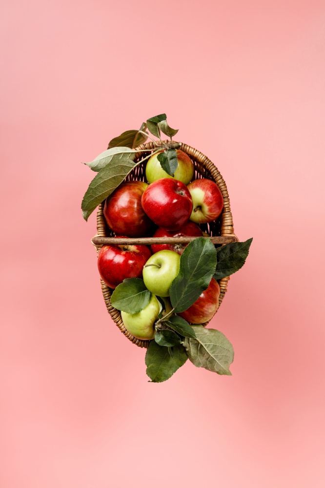 Organic apples in basket on pink background, flat lay