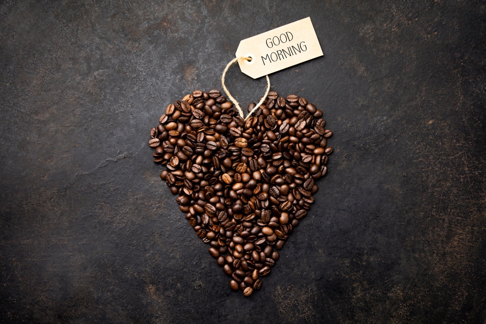 Coffee beans in shape of heart on dark rustic background, flat lay