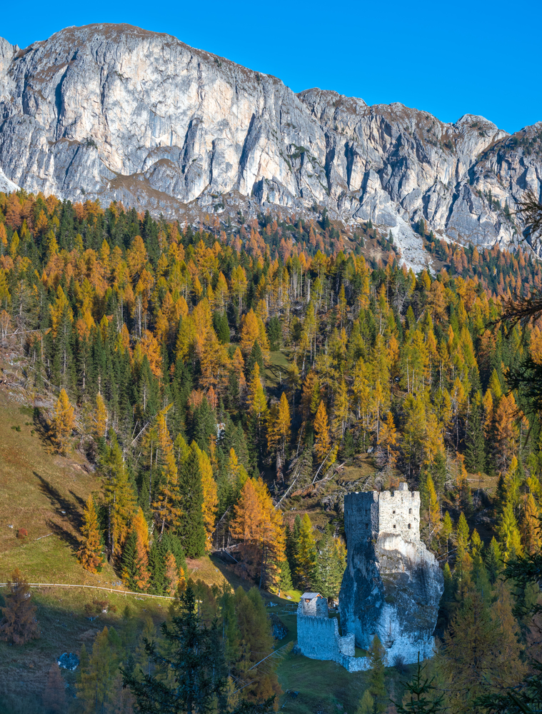 Sunny autumn alpine Dolomites mountain scene, Italy. Falzarego Path and Ruins of Andraz castle view. Picturesque traveling, seasonal, nature and countryside beauty concept scene.
