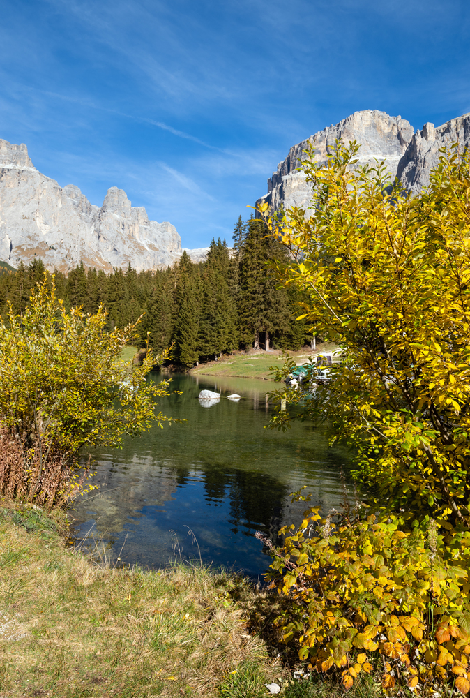 Autumn alpine Dolomites mountain and lake scene, Sudtirol, Italy. Peaceful view near Sella Pass. Picturesque traveling, seasonal, nature and countryside beauty concept scene.