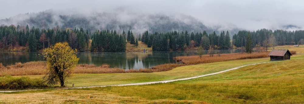 Alpine  lake Geroldee or Wagenbruchsee, Bavaria, Germany. Autumn overcast, foggy and drizzle day. Picturesque traveling, seasonal, weather, and rural nature beauty concept scene.