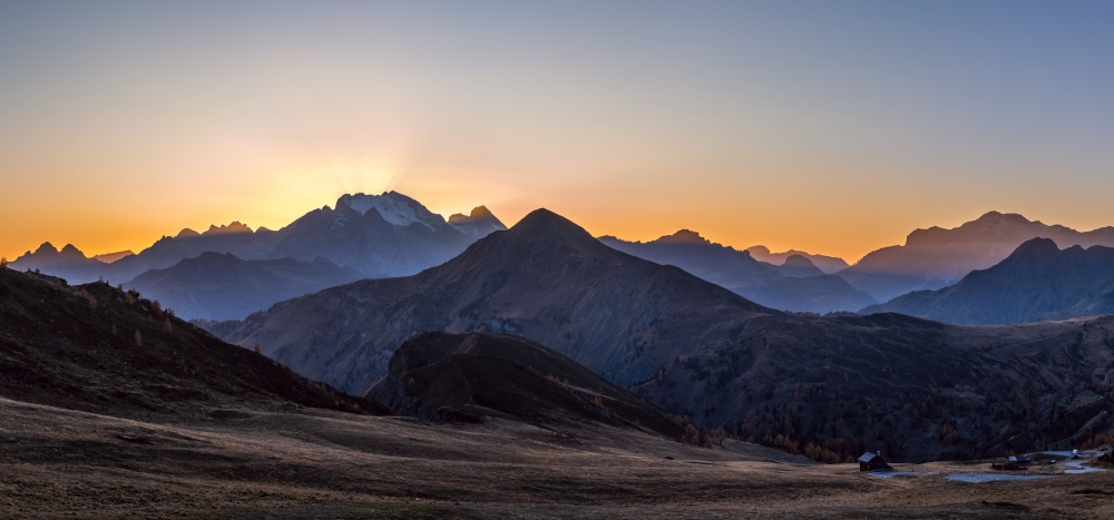 Sun glow and lust sunlight in evening hazy sky. Italian Dolomites mountain panoramic peaceful view from Giau Pass. Climate, environment and travel concept scene.