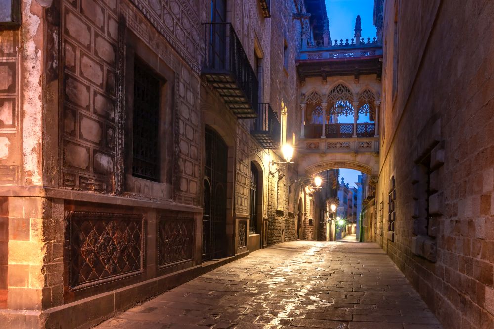 Narrow cobbled medieval Carrer del Bisbe street with Bridge of Sighs in Barri Gothic Quarter in the morning, Barcelona, Catalonia, Spain. Bridge of Sighs in Gothic Quarter, Barcelona