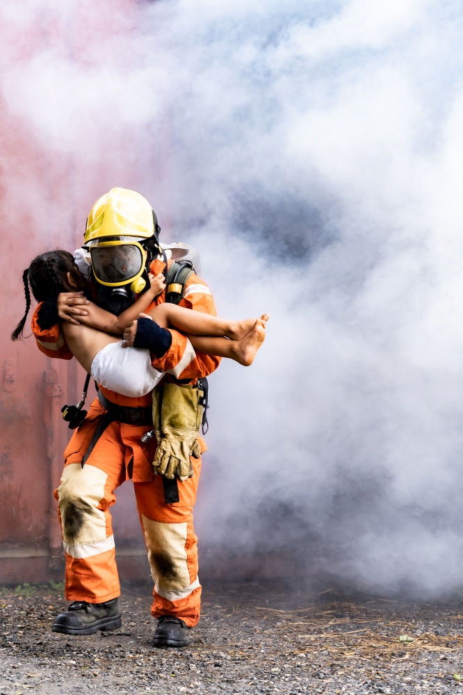 Firefighter rescue girl little child from burning building. He hold the girl and run out through smoke from building. Firefighter safety rescue from accident and public service concept.