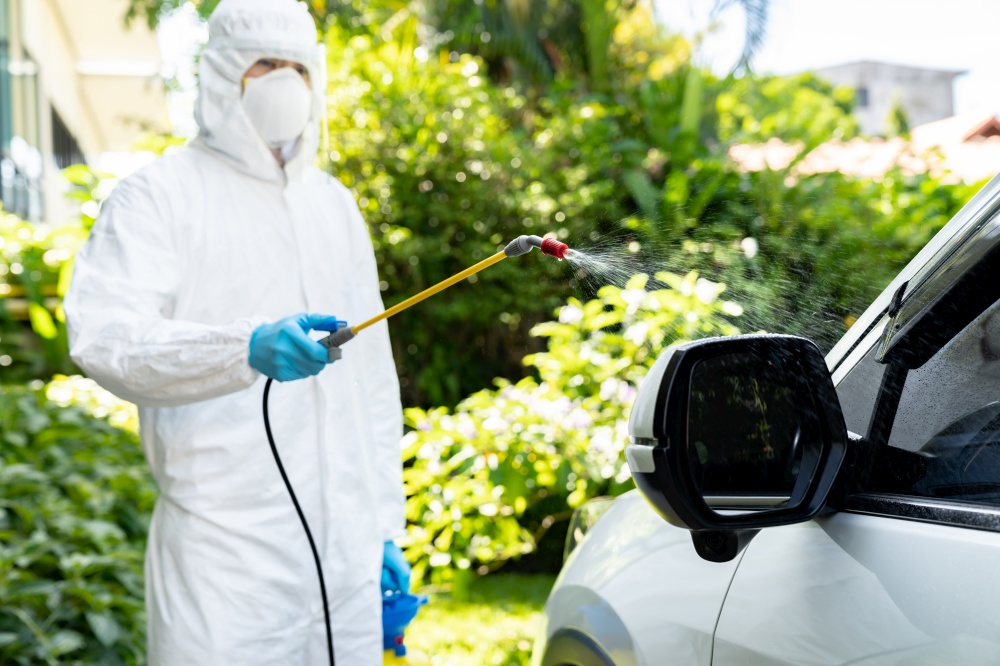 Car cleaning using chemical alcohol spray to disinfect and decontaminate coronavirus covid-19 by specialist cleaner wear personal protective equipment PPE. New normal Hygiene concept.